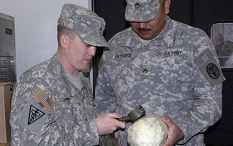 Sgt. Joshua Jones, left, a food inspector, and Staff Sgt. Fernando Ontiveros, radiation monitoring coordinator, test a head of lettuce for surface radiation during a routine inspection in March.