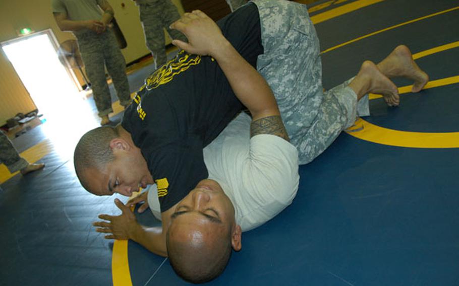 Combatives instructor Army Sgt. Matthew Prout, 26, of Baltimore, top, demonstrates a grappling technique with help from Air Force Tech Sgt. Jordan Acosta, 29, of Wahiawa, Hawaii, at Yokota Air Base on June 24, 2011.