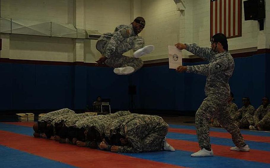 Spc. Michael Boney jumps over fellow members of the 2nd Infantry Division's Tae Kwon Do Demonstration Team to kick apart a board being held by Pfc. Clifford Labowsky during a performance Aug. 3, 2011, at Camp Red Cloud in South Korea. The team does about 15 demonstrations a year.