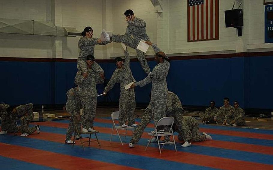 Korean Pfc. Cho Jin-hee, center, breaks board after launching himself into the air off fellow 2nd Infantry Division Tae Kwon Do Demonstration Team members Aug. 3, 2011, at Camp Red Cloud in South Korea.