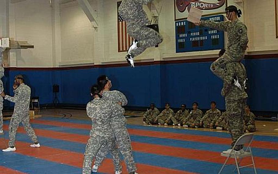 With some help from a couple of his fellow 2nd Infantry Division Tae Kwon Do Demonstration Team members, Spc. Brandon Henderson launches himself into the air to break a board held about 10 feet in the air. The feat was performed during a demonstration Aug. 3, 2011, at Camp Red Cloud in South Korea.