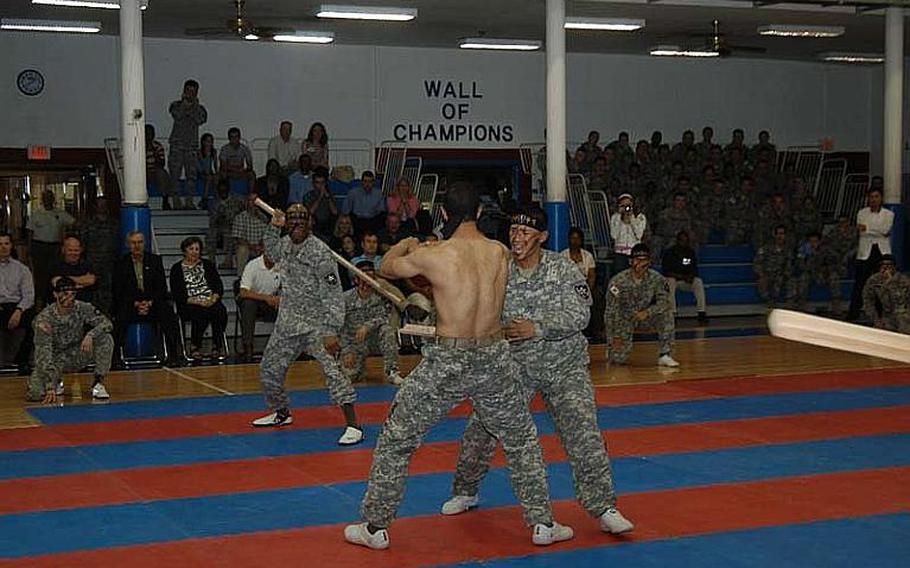 Pfc. Christopher Brown, shirtless, is struck across the midsection by a piece of wood swung by Pfc. Marjany Bolling during a 2nd Infantry Division Tae Kwon Do Demonstration Team performance Aug. 3, 2011, at Camp Red Cloud in South Korea.