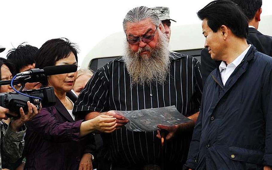 Steve House, center, looks at a map of the area surrounding Camp Carroll's helipad during a visit to the Daegu-area base on July 27, 2011. House claims he buried Agent Orange in a ditch at the base while stationed there in 1978, and told officials they were not searching the location where he remembered the ditch being located.