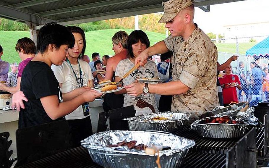 Lance Cpl. Mark Massone, serves up a hamburger to one of the 25 school children from Oshima District, Kesennuma City, Miyagi Prefecture. Their town was heavily damaged in the March 11 East Japan Great Earthquake and they visited Okinawa as part of a four-day cultural exchange/homestay program sponsored by Marine Corps Bases Japan.