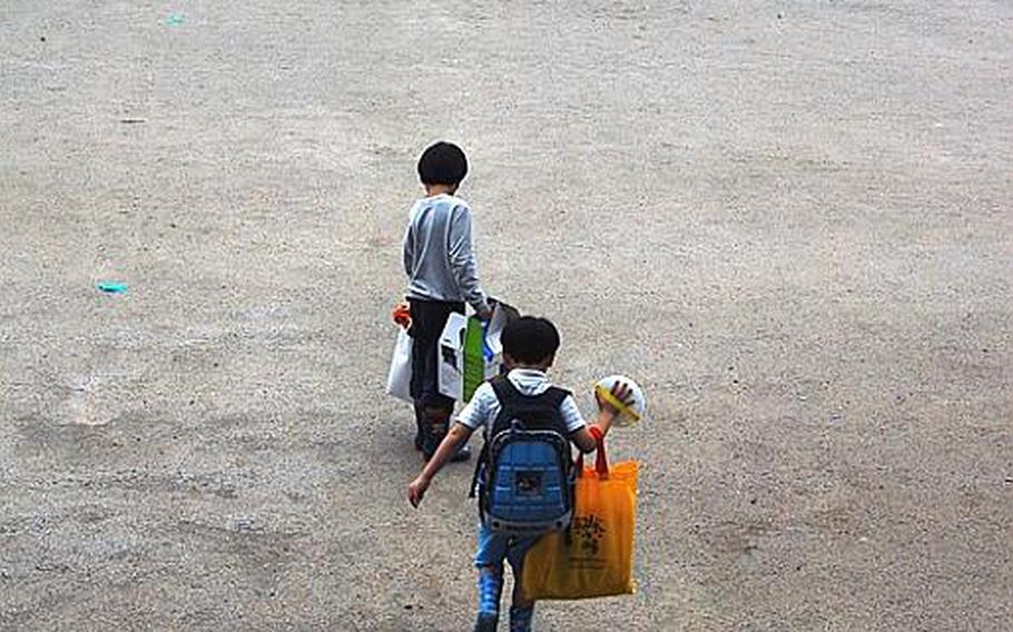 Students walk across Taesongdong Elementary School's soccer field at the end of the school day to board a bus that will take them home.