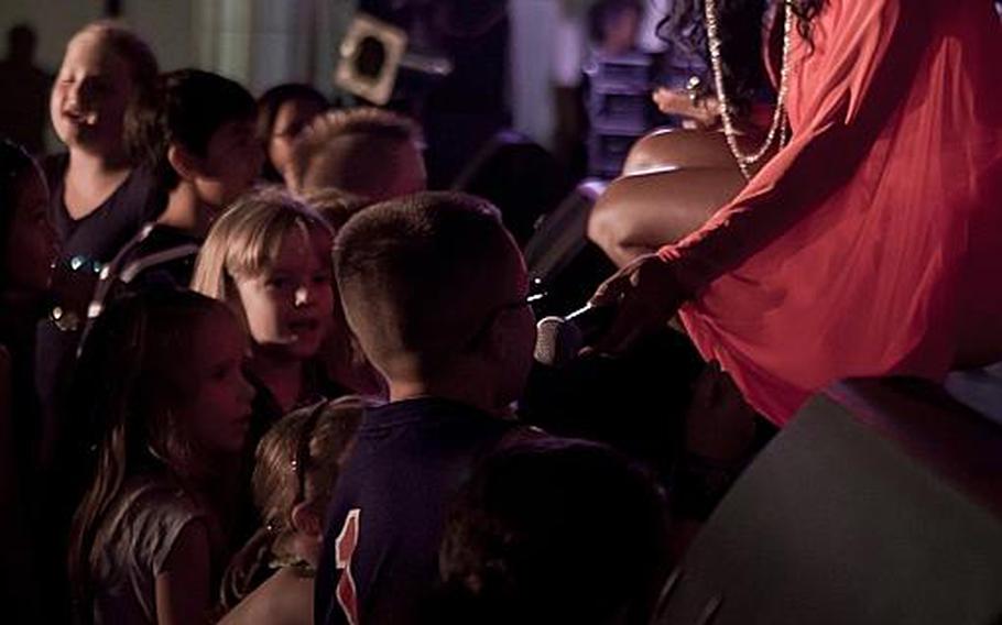 Past American Idol contestant Ta-Tynisa Wilson shares the microphone with a young fan Wednesday night during a performance at Yokota Air Base.