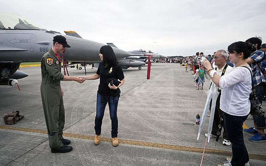 Capt. Chris "Thud" Beherens, with the 13th Fighter Squadron out of Misawa Air Base, Japan, poses for photos with visitors Aug. 20, 2011, during the Japanese-American Friendship Festival at Yokota Air Base, Japan.