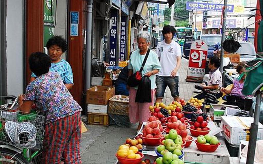 Women talk in front of a fruit stand on a busy street in the heart of Waegwan in South Korea. Concerns over possible exposure to Agent Orange, has led the South Korean government to conduct a health study on residents living near Camp Carroll.