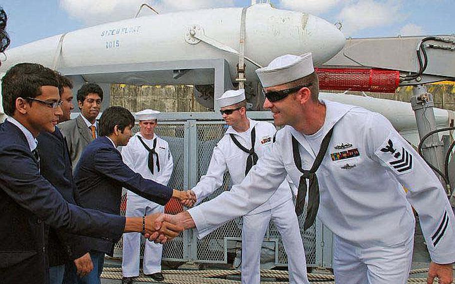 Mineman 1st Class Ben Hall and Mineman 3rd Class Zach Abel greet high school students from Chittagong Grammar School mONDAY during a ship tour of the Sasebo-based USS Defender, during Cooperation Afloat Readiness and Training (CARAT) Bangladesh 2011. CARAT 2011 is a series of bilateral exercises held annually in Southeast Asia to strengthen relationships and enhance force readiness.