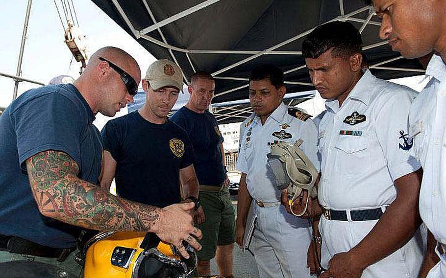 Petty Officer 2nd Class Taylor Nevius, a Navy diver from Mobile Diving and Salvage Unit 1, explains a KM-37 Deep Sea Diving Helmet to divers from the Bangladesh navy aboard USNS Safeguard. Safeguard is in Chittagong for Cooperation Afloat Readiness and Training (CARAT) Bangladesh 2011. CARAT is a series of bilateral exercises held annually in Southeast Asia to strengthen relationships and enhance force readiness. CARAT Bangladesh 2011 marks the first time the Bangladesh navy has participated in the exercise series.