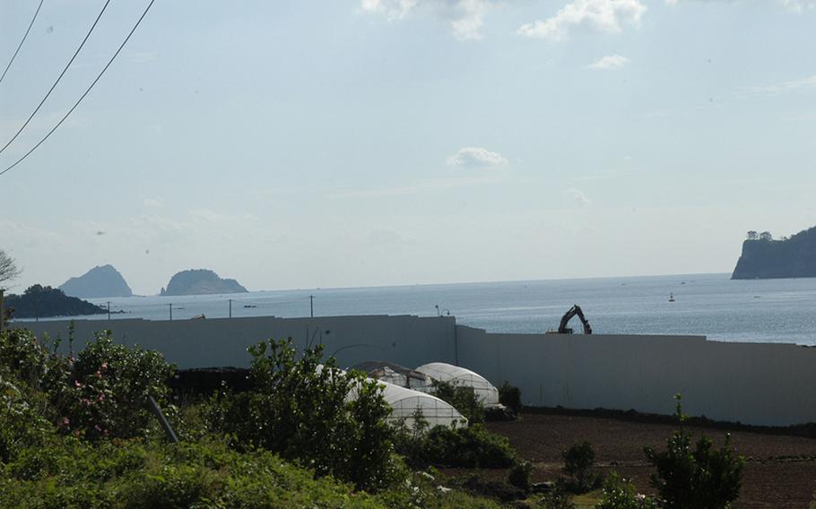 Construction equipment is visible behind a wall on Jeju Island in South Korea where South Korea is building a controversial naval base. Officials say the base will better enable the South Korean navy to police sea lanes south of the island.