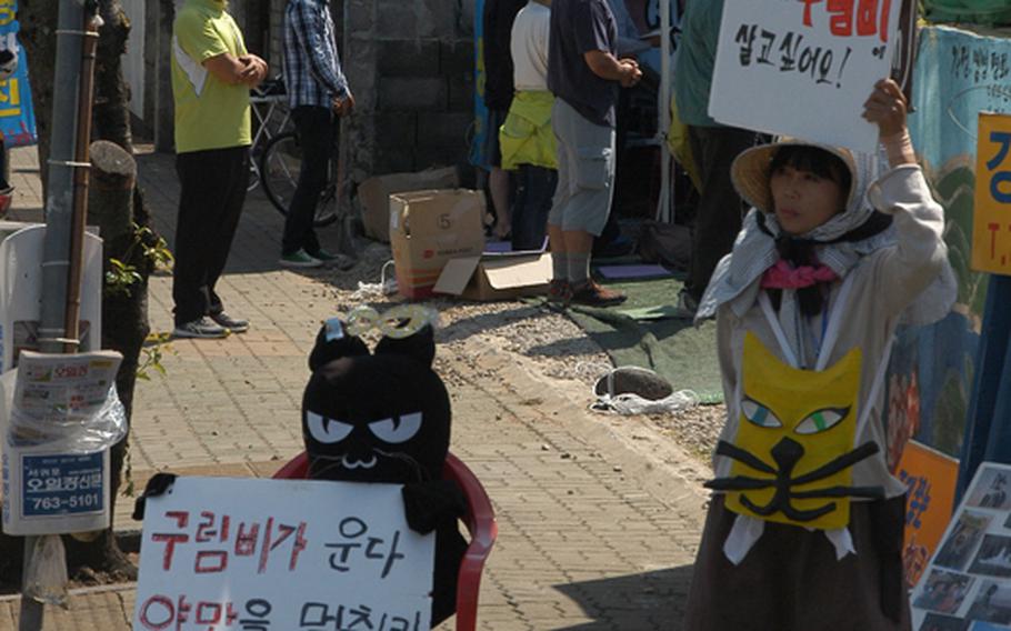 An opponent of a naval base being built on Jeju Island in South Korea holds up a protest sign in Gangjeong, a village near the construction site.