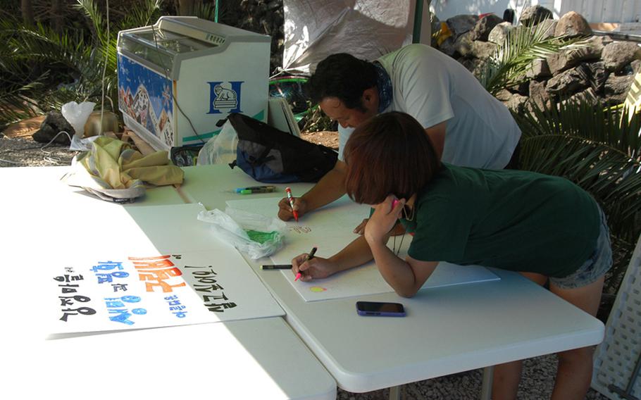 Opponents of a naval base being built on Jeju Island in South Korea work on protest signs near the construction site.