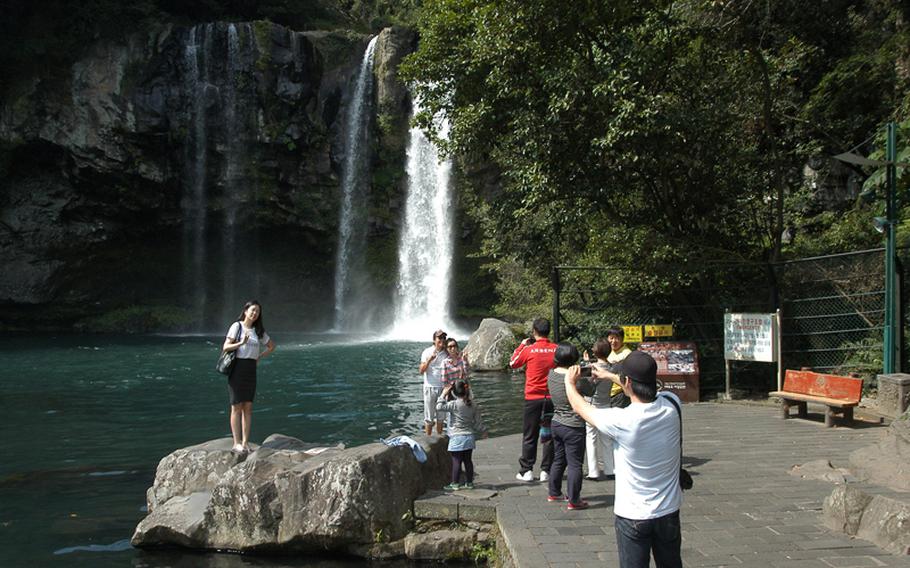Visitors pose for photos at Cheonjiyeon Falls, one of many natural wonders on Jeju Island in South Korea. Residents of the island are divided on whether a South Korean naval base under construction there is a good idea given Jeju's natural beauty and designation as an "island of world peace."