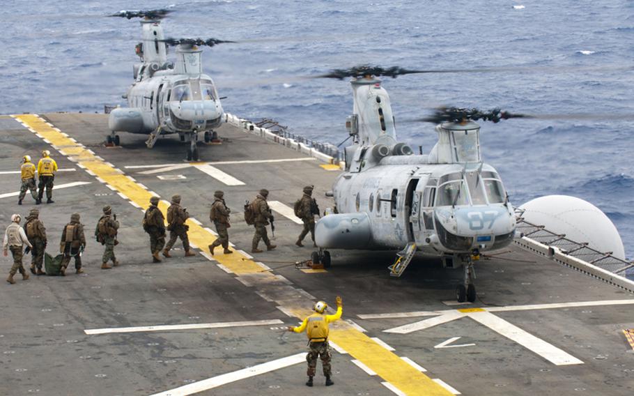 Marines assigned to the 31st Marine Expeditionary Unit board a CH-46E Sea Knight for a simulated air raid from the Philippine Sea aboard the forward-deployed amphibious assault ship USS Essex on Oct. 2, 2011.