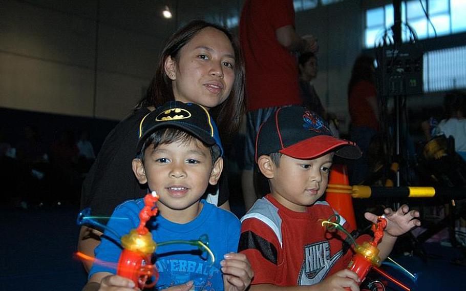 Jermaine Aterrado, 4, (left), and his brother Cedrick, 3, are lost in their glow toys before the  Sesame Street/USO Experience for Military Families show Oct. 6, 2011, at Sasebo Naval Base, Japan. Their mother, Jinky Aterrado, looks on.