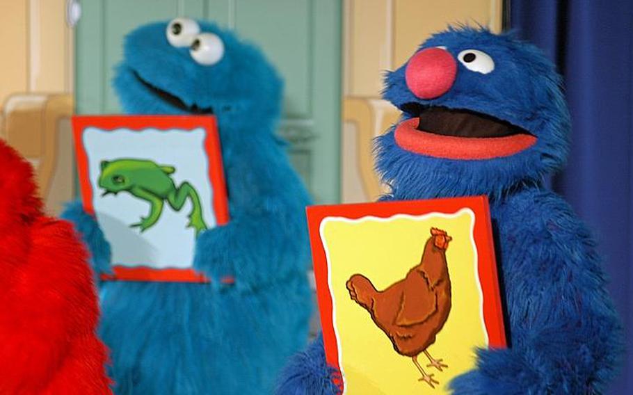 Grover, foreground, and Cookie Monster explain through song and visuals that change can be good during the Sesame Street/USO Experience for Military Families show Oct. 6, 2011, at Sasebo Naval Base, Japan.