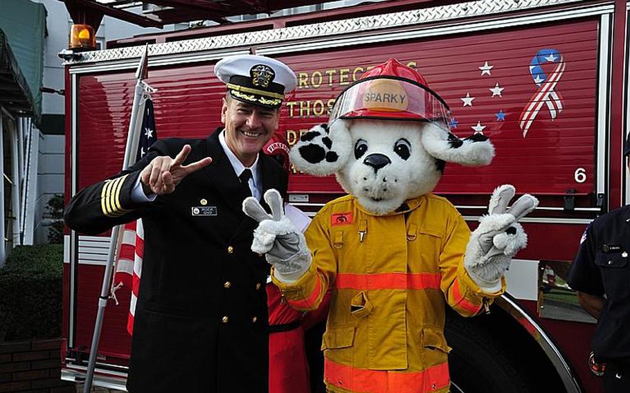 Commander Fleet Activities Sasebo Capt. Charles Rock, left, poses for a photo with Sparky, Fire Prevention Week's mascot, after signing a proclamation Tuesday morning to declare Oct. 9-15 Fire Prevention Week at the base. This year, Sparky celebrates his 60th birthday.