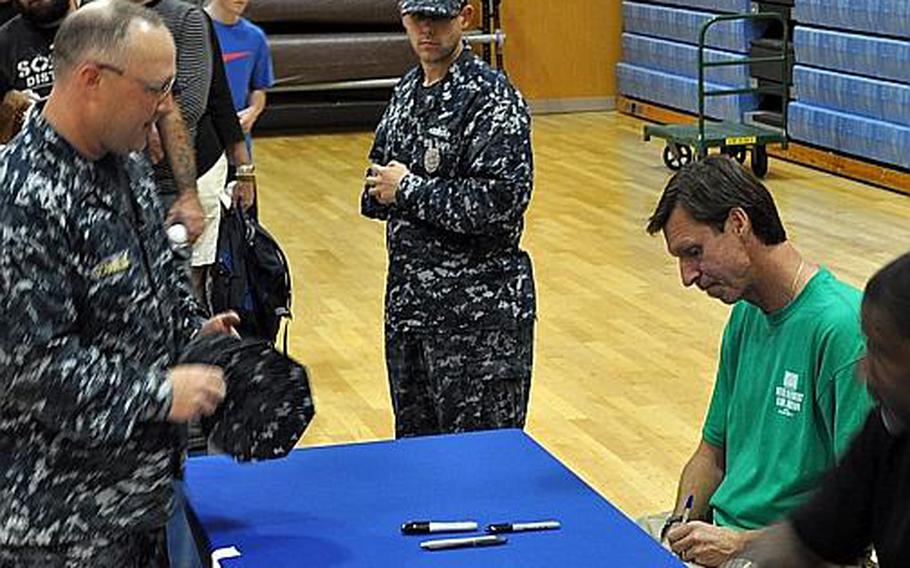 Retired Major League star Randy Johnson signs a baseball for a fan at the Fleet Recreation Center gym at Yokosuka Naval Base, Japan, on Oct. 11, 2011. Dennis Haysbert (partially seen on the right) from the TV show "The Unit," was also there to sign autographs and take photos with fans.