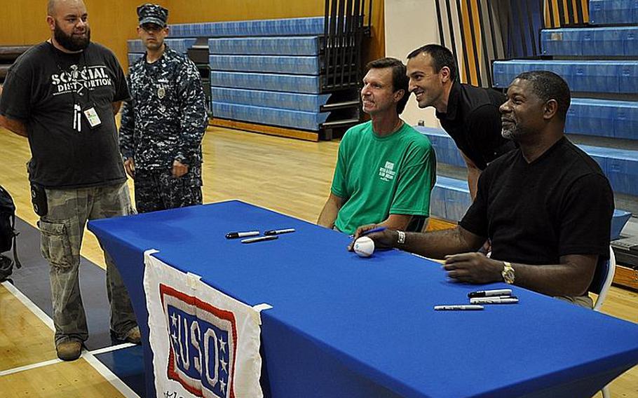 Randy Johnson, retired Major League Baseball star, and actor Dennis Haysbert, star of the TV show "The Unit," smile for the camera as they have their picture taken with a fan at the Fleet Recreation Center gym at Yokosuka Naval Base, Japan, on Oct. 11, 2011. Fans brought baseball caps, DVDs and other memorabilia for the two stars to autograph.