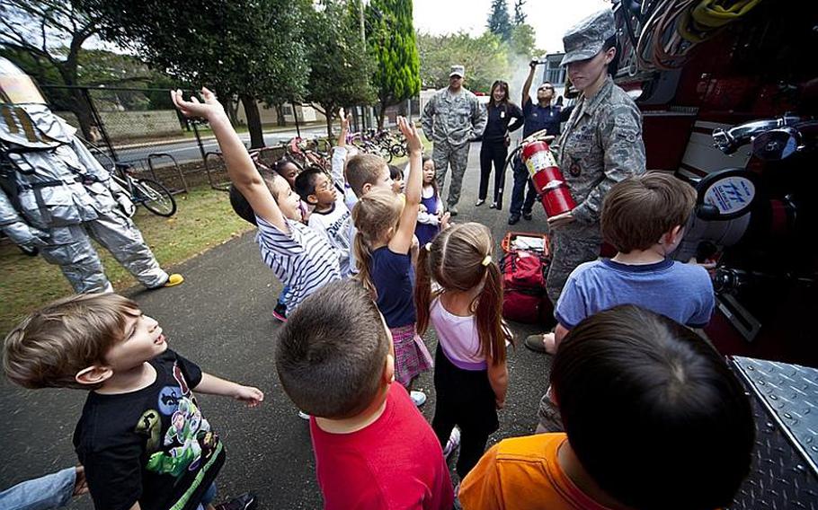 Airman Taylor Robinett, a firefighter with the 374th Civil Engineer Squadron at Yokota Air Base, explains the proper use of a fire extinguisher to Betty-Ann Stinson's kindergarten class at Joan K. Mendel Elementary School, part of the National Fire Prevention Week campaign.