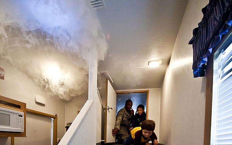 Joshua Itule, a first-grader at Joan K. Mendel Elementary School, crawls to safety from a room filled with fake smoke during a National Fire Prevention Week activity Oct. 12, 2011, at Yokota Air Base, Japan. 