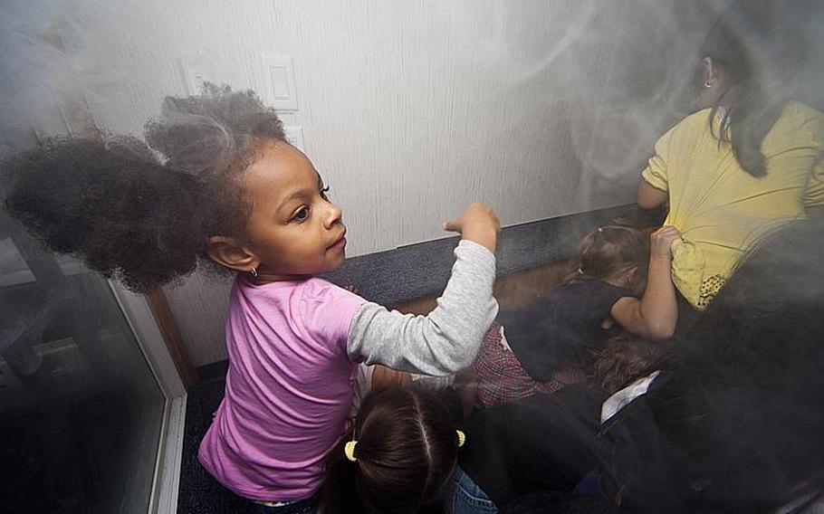 Krisel Se'Aunna, a kindergarten student at Joan K. Mendel Elementary School at Yokota Air Base, reacts to the room filling up with fake smoke during a National Fire Prevention Week activity on Oct. 13, 2011. The students were learning what to do in the event of a fire. 