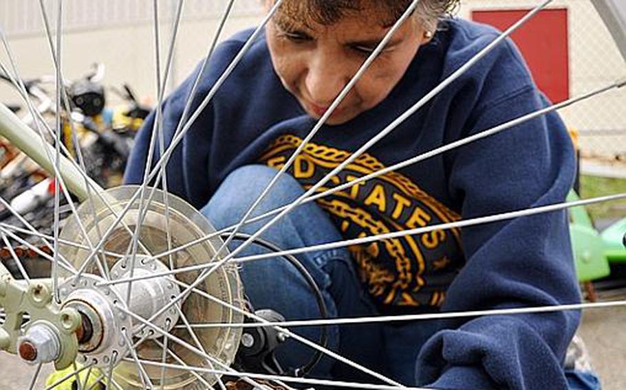 Lydia DeLeon-Rush cleans rust from the chains of an abandoned bicycle at Yokosuka Naval Base, Japan. She has collected bicycles to repair and give to Japanese families affected by the earthquake and tsunami earlier this year.