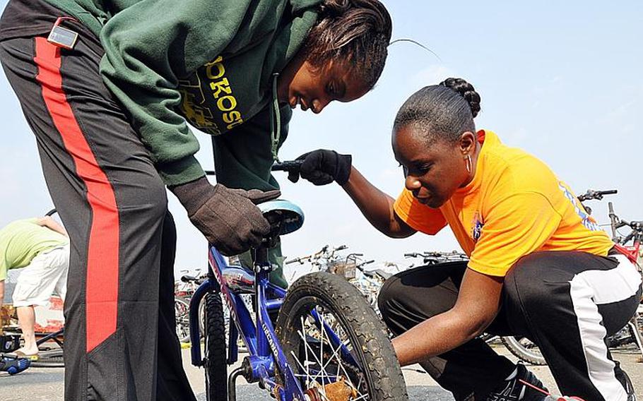 Andrea Brown, right, a teacher at the Sulivan school at Yokosuka, and her daughter De'Asia help to prepare abandoned bicycles to be sent to families in need.