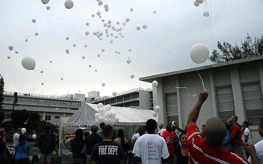 Parents, children and friends release balloons with the names of babies who passed away during pregnancy during a Walk to Remember memorial service held Oct. 15, 2011, at Camp Lester on Okinawa. The walk allows parents who have lost of a young child to come together as a group to remember their children.