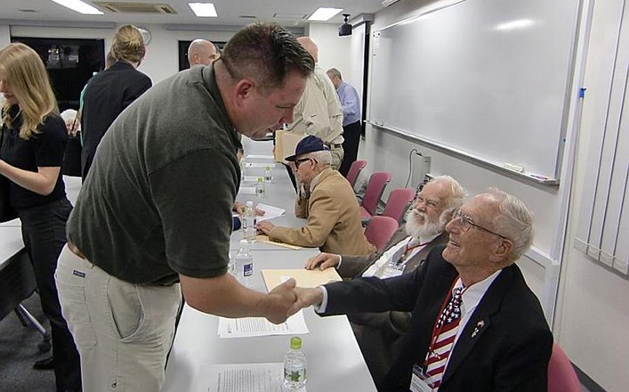 Army Col. Jeff Oppenheim, left, shakes hands with 91-year-old Harold A. Bergbower, following a lecture at Temple University on Oct. 17, 2011, in Tokyo. Bergbower and six other WWII POWs are touring Japan this week this week seeking closure to the brutal treatment they endured while held captive.