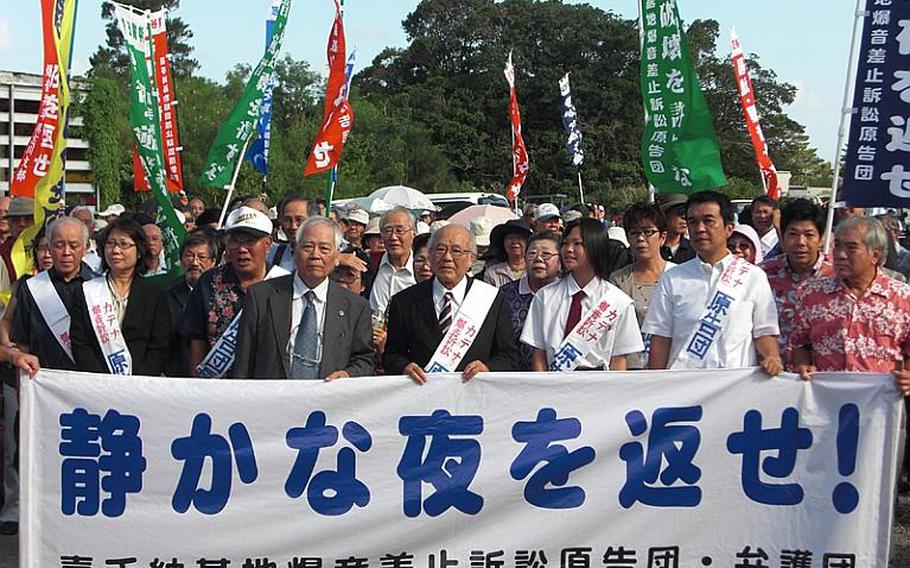 About 300 residents and their supporters held a rally Oct. 20, 2011, near the Okinawa Branch of Naha District Court before an opening hearing on lawsuit filed against the Japanese government by more than 22,000 residents near Kadena Air Base over aircraft noise emitted from the air base. The banner reads 'Give us back quiet evening hours.'