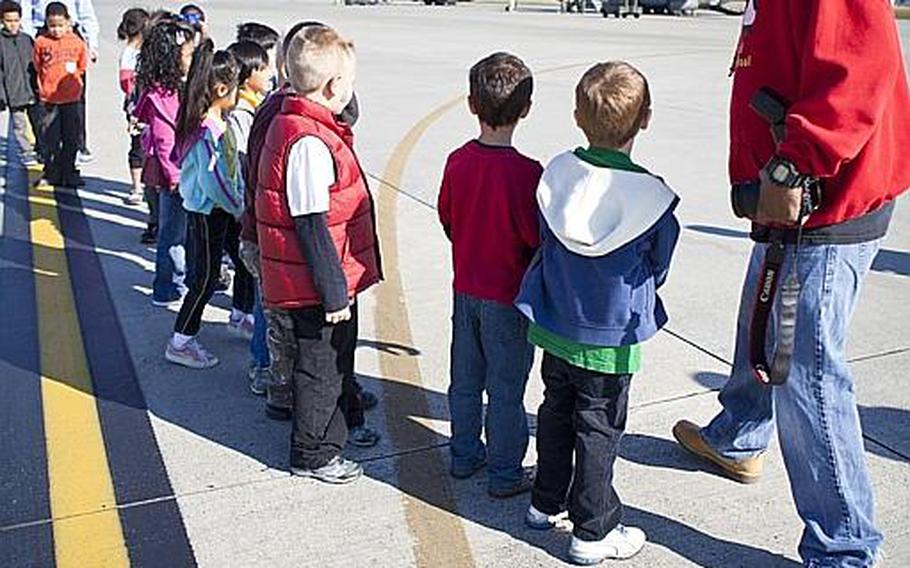First-graders from Samuel Montgomery's class at Joan K. Mendel Elementary lined up along the flight line Nov. 2, 2011, at Yokota Air Base, Japan, to tour a C-130 cargo plane and UH-1 helicopter.