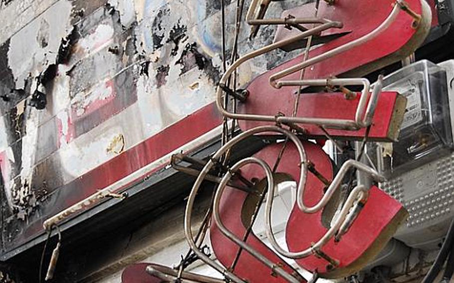 Part of a burned sign hangs near the entrance of Tiger Tavern, a club in Itaewon's Hooker Hill district. A U.S. soldier allegedly set fire Tuesday to the club, which is off-limits for U.S. military personnel because of its suspected involvment in prostitution and human trafficking.