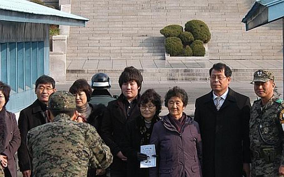 Members of the family of Cpl. Jang Myunk-ki pose for photos at the Demilitarized Zone in Korea as a North Korean soldier looks on from the other side of the Military Demarcation Line. The family was at the DMZ on Nov. 23, 2011, for a ceremony marking the 27th anniversary of a firefight in which Jang, a Korean augmentee to the U.S. Army, was killed.

