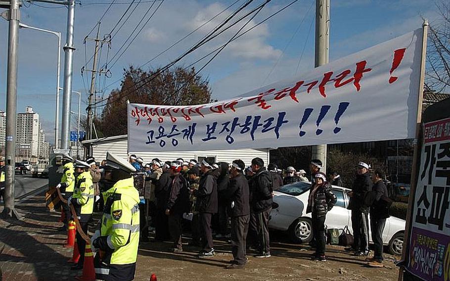 South Korean police standby Dec. 1, 2011, near a group of security guards protesting across the street from Camp Red Cloud in Uijeongbu. The guards are upset that the company that the week of Nov. 28 took over security for U.S. Army installations in South Korea will only hire them if they accept less pay and longer hours than they worked for the company that formally held the security contract.