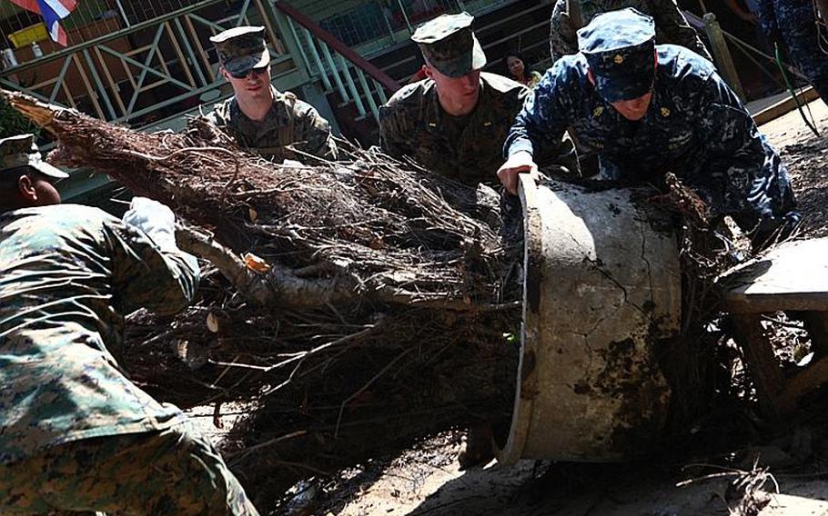 U.S. service members remove fallen debris at the Sanamchai School in Lop Buri on Nov. 20, 2011. Joint U.S. forces came together to assist the Royal Thai Army Special Warfare College clean community facilities. U.S. forces continue to support the Royal Government of Thailand in their flood relief efforts.