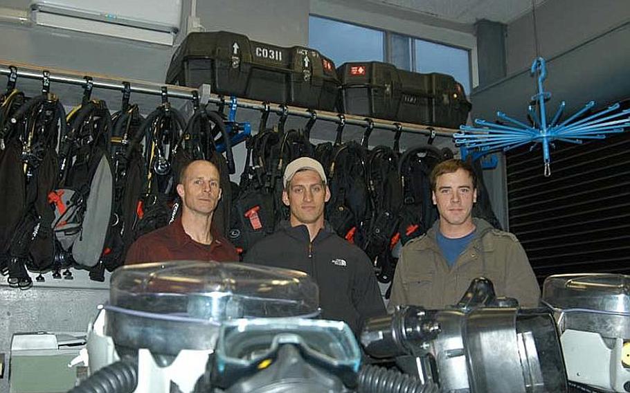 From left to right, Petty Officer 1st Class Corey Baughman, Petty Officer 1st Class Dillon Mudloff, and Petty Officer 3rd Class Adam Andryc, of Explosive Ordinance Disposal Mobile Unit 5, Detachment 51, pose in their shop with their bomb disposal gear. The trio of bomb technicians saved the life of a Japanese national while climbing Mt. Fuji on Dec. 9-12, 2011. The sailors got more than they bargained for on what turned out to be a harrowing weekend on the mountain. Baughman suffered frostbite staying on the mountain overnight with the man after he fell. Baughman's efforts helped the man fight off shock and certain death. The man was rescued the next day.