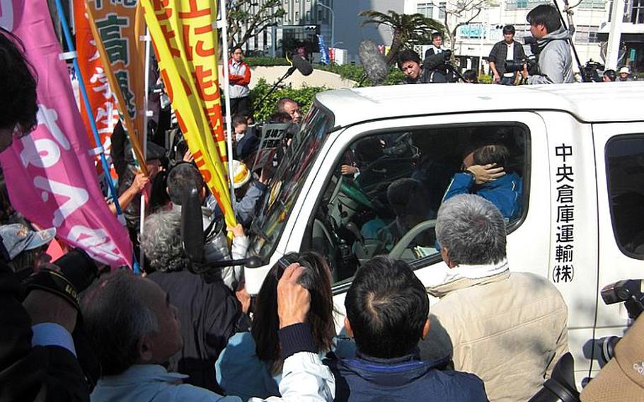 Protesters opposing a new Marine Corps runway in Henoko, Okinawa, surround a van on Dec. 27, 2011, preventing a delivery of an environmental impact assessment report to Okinawa prefectural government. The report submission is a necessary procedure under Japanese environmental law. Tokyo is moving forward with the construction of V-shaped runway, planned to extend into reclaimed land in Henoko Bay, adjacent to Camp Schwab.