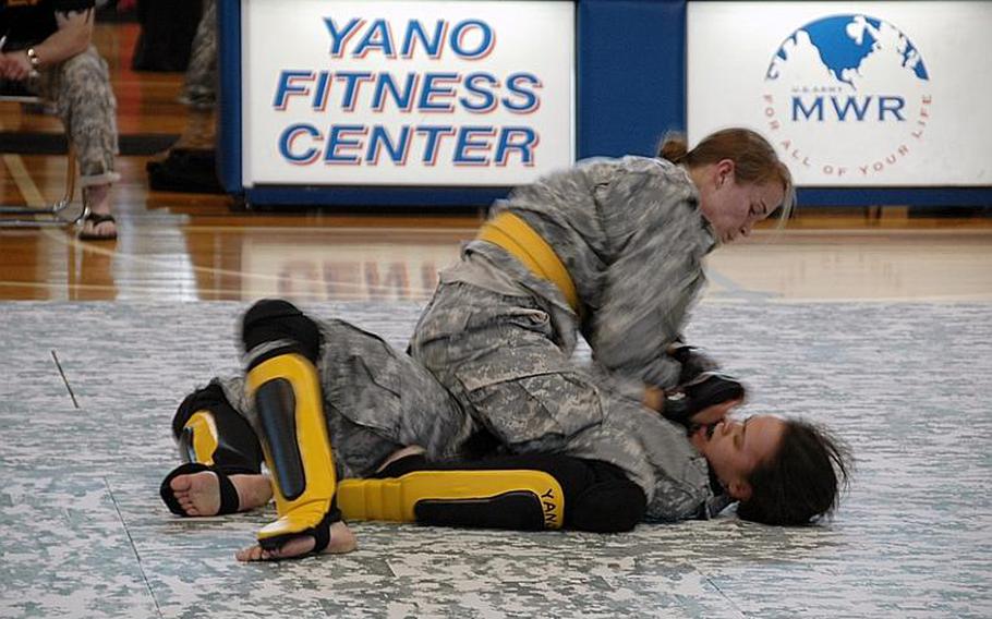 Staff Sgt. Quail Hjelmeir, top, grapples with Spc. Melissa Myers during a U.S. Army Combatives tournament at Camp Zama in December 2011. Myers defeated Hjelmeir to win the flyweight division. 
