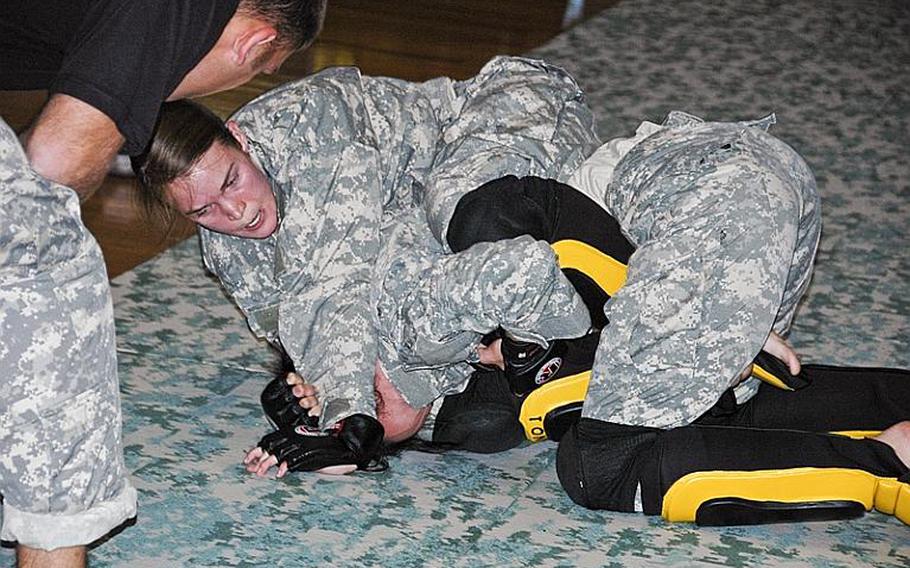 Staff Sgt. Quail Hjelmeir, top, grapples with Spc. Melissa Myers during a U.S. Army Combatives tournament at Camp Zama in December 2011. Myers defeated Hjelmeir to win the flyweight division. 