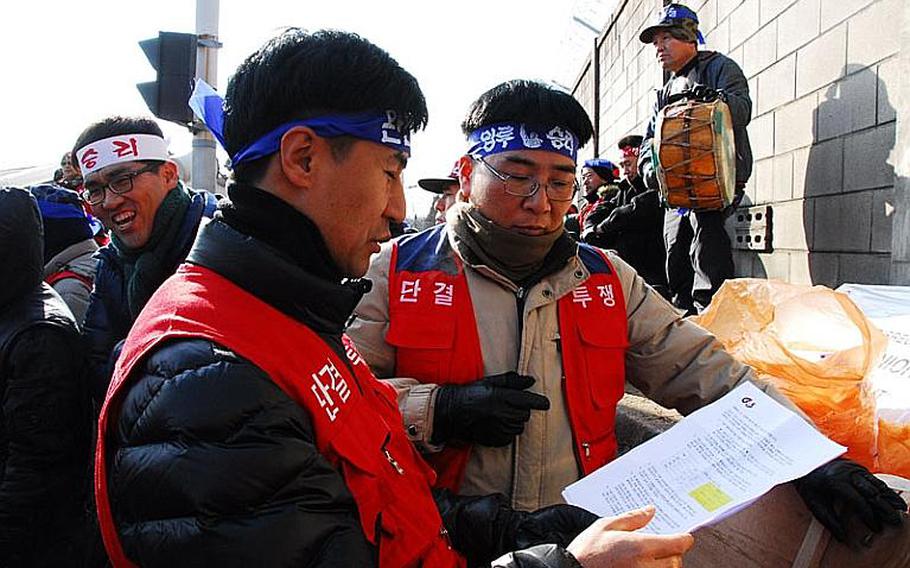 Former security guard Chon Woo-nam, front left, examines a proposed contract on Jan. 11, 2012, from G4S, the company responsible for providing guards for entry points at most U.S. military installations in South Korea. Since G4S' contract went into effect in December 2011, many guards for the previous security guard company have refused to work for G4S because of disputes over working hours and pay.