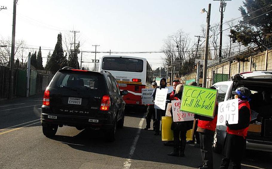 Former security guards hold up signs as cars enter U.S. Army Garrison-Yongsan on Jan. 11, 2012. Hundreds of former security guards have refused to work for G4S, the contractor responsible for providing security at entry points at most U.S. military installations in South Korea, since the company's contract went into effect last month.