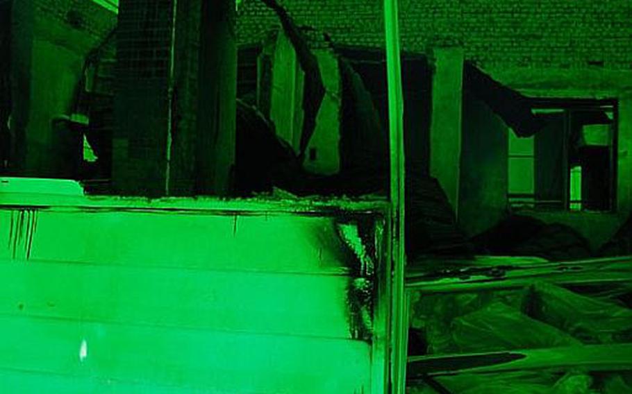 The remains of a bombed house in the middle of the main village on Yeonpyeong Island. What remains are hidden under a massive green tarp, giving the setting an eerie glow. Passersby can view the buildings by looking through a doorway cut into the tarp.
