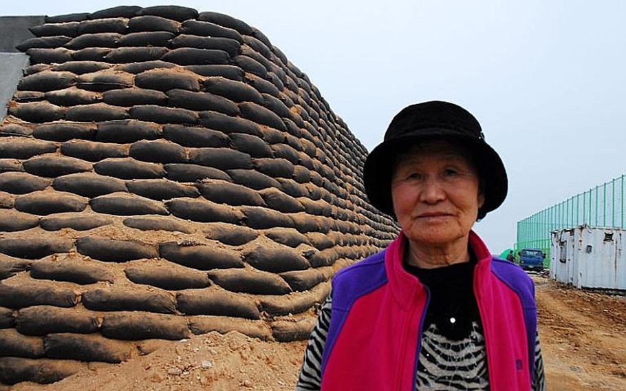 Kim Sun-young, 72, stands outside a bomb shelter now under construction across the street from her home on Yeonpyeong Island, which was shelled by North Korea in November 2010. Kim said she does not believe the shelter will keep people safe because it is built above ground.