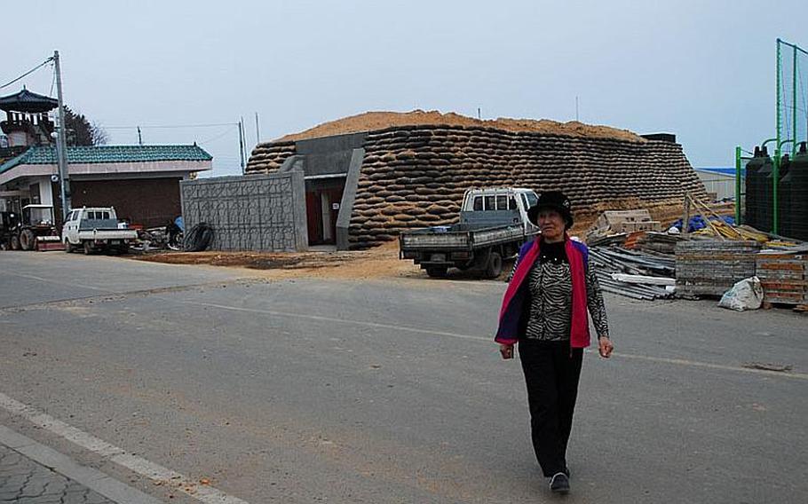Kim Sun-young, 72, walks in front of a bomb shelter now under construction across the street from her home on Yeonpyeong Island, which was shelled by North Korea in November 2010.
