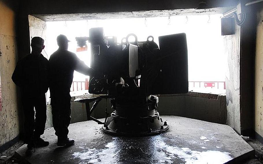 Two visitors at an underground tunnel on Yeonpyeong Island look at an old piece of artillery, aimed at North Korea, on display for tourists.