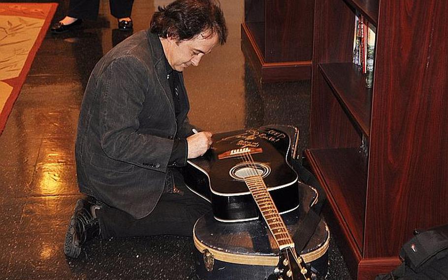 Guitarist Brent Look signs a guitar for the United Service Organizations office during a visit to the Yokosuka Naval Base on March 18, 2012. Look played guitar for Creed singer Scott Stapp at a concert aboard the USS George Washington.
