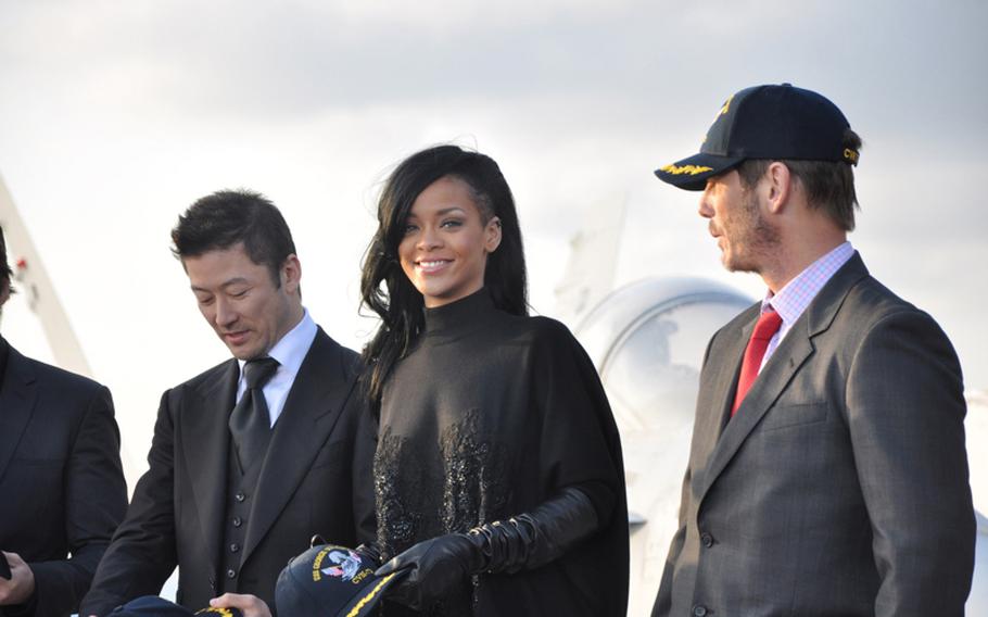 The cast and crew from the movie "Battleship" accept USS George Washington caps aboard the aircraft carrier following a press conference on the flight deck Monday. Pictured from left are Japanese actor Tadanobu Asano; pop singer Rihanna, who makes her acting debut in the film; and director Peter Berg.