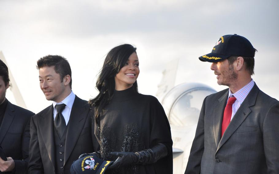 The cast and crew from the movie Battleship accept USS George Washington caps aboard the aircraft carrier following a press conference on the flight deck Monday. Pictured from left are Japanese actor Tadanobu Asano; pop singer Rihanna, who makes her acting debut in the film; and director Peter Berg.